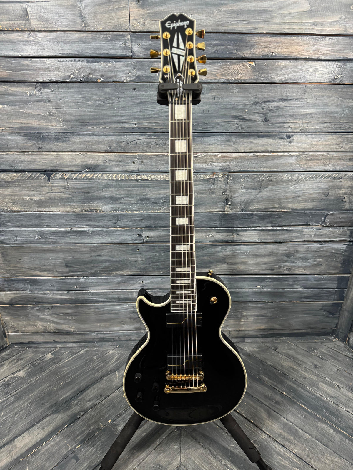 Black electric guitar with gold hardware on a wooden background