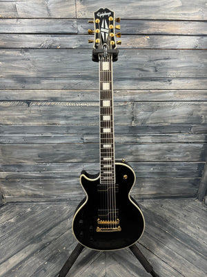 Black electric guitar with gold hardware on a wooden background