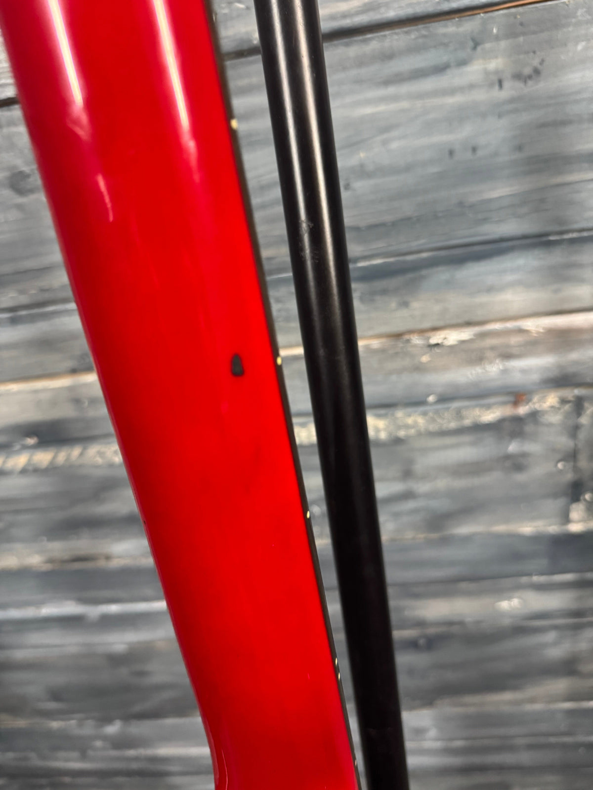 Close-up of a red object with a black rod against a wooden background
