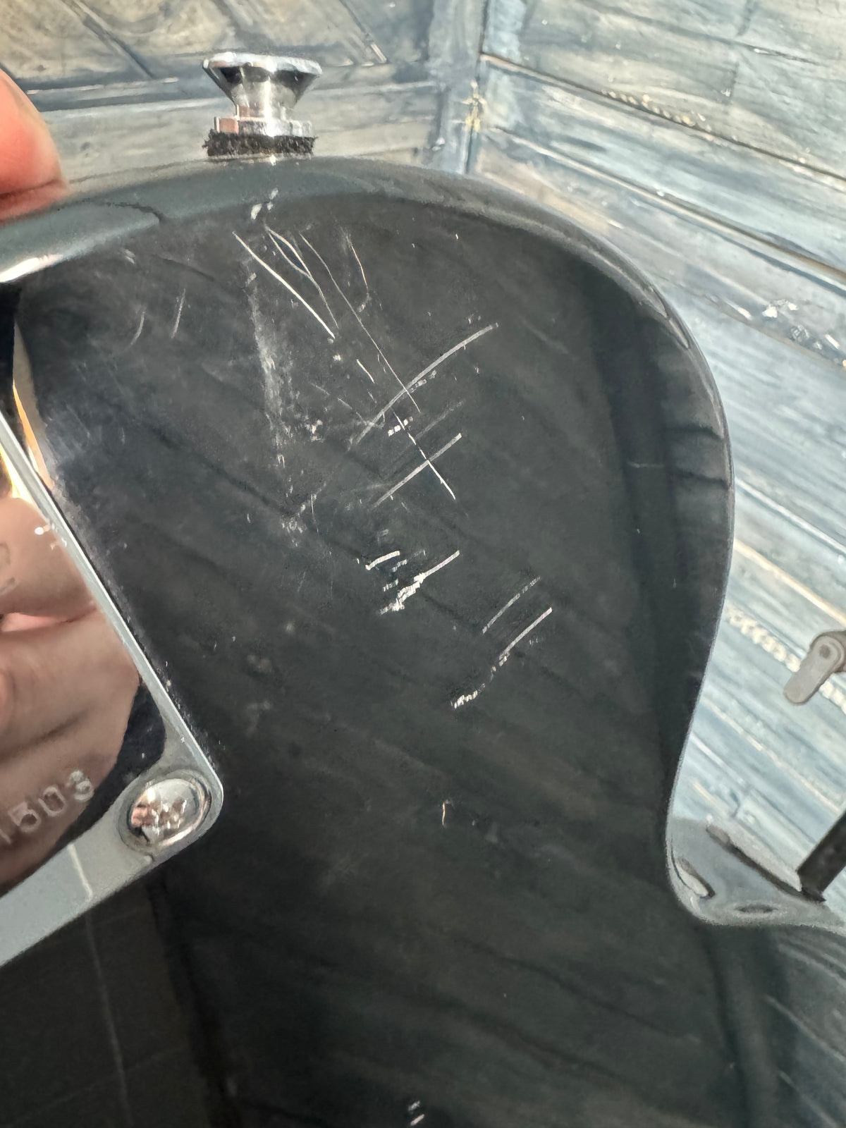 Close-up of a guitar case with visible scratches and a person's hand holding it.