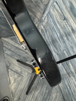 Black guitar case with a yellow label on a wooden floor