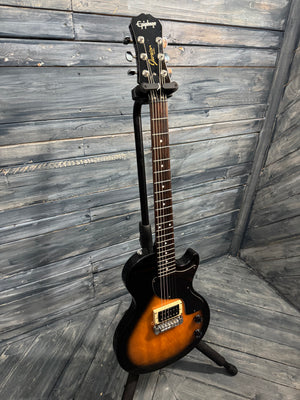 Electric guitar on a stand against a wooden wall