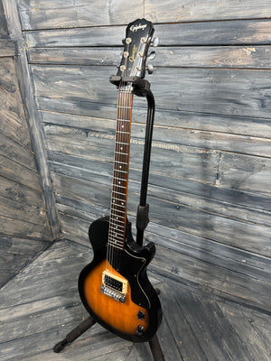 Electric guitar on a stand against a wooden wall