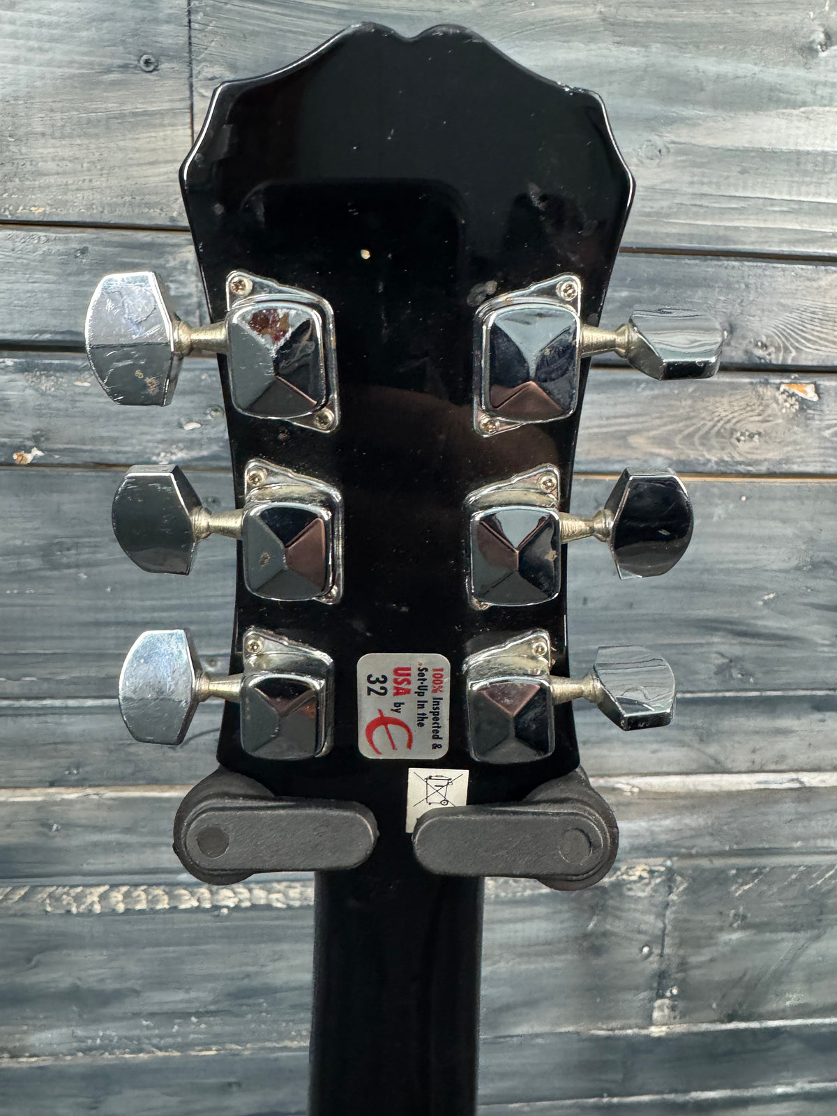 Guitar headstock with tuning pegs on a wooden background