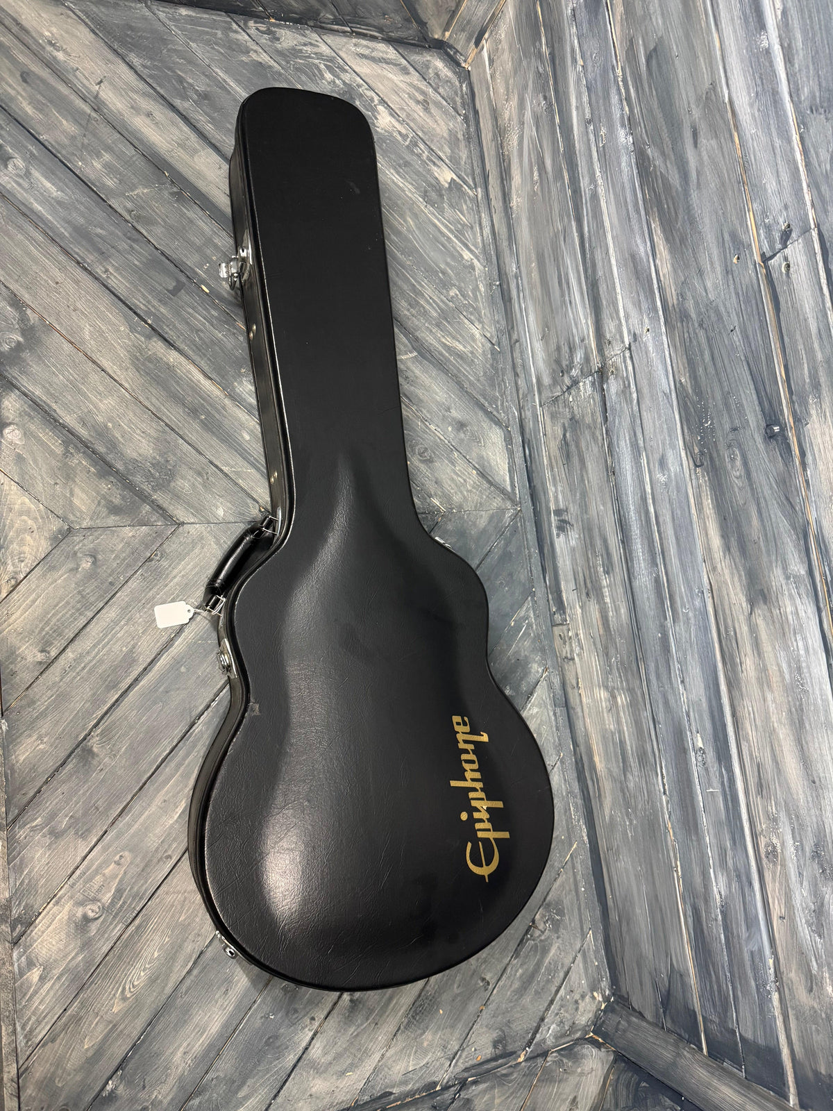 Black guitar case with 'Epiphone' branding on a wooden floor.