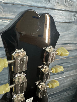 Close-up of a guitar's headstock with tuning pegs on a wooden surface