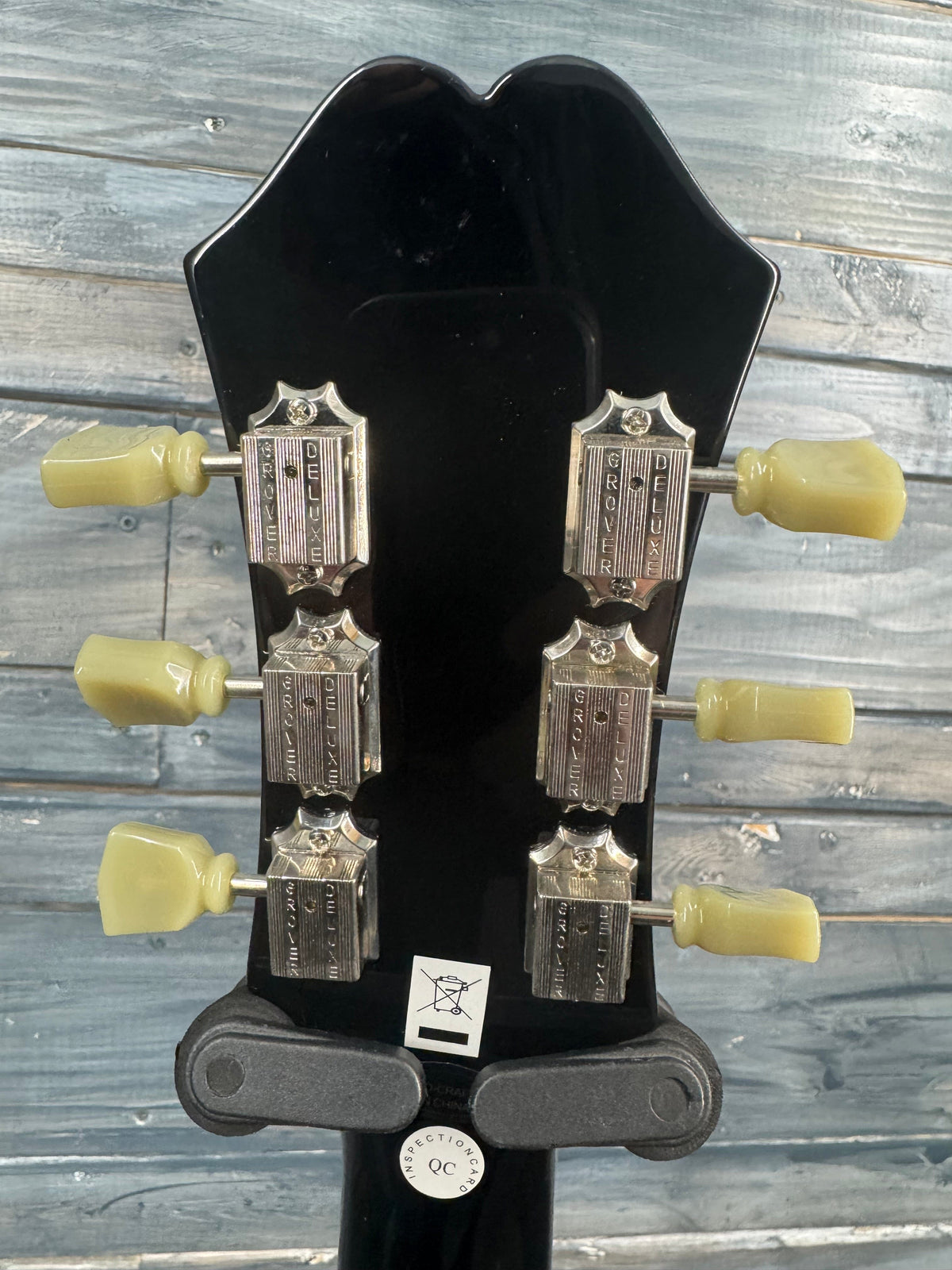Close-up of a guitar's truss rod cover with tuning pegs on a wooden background