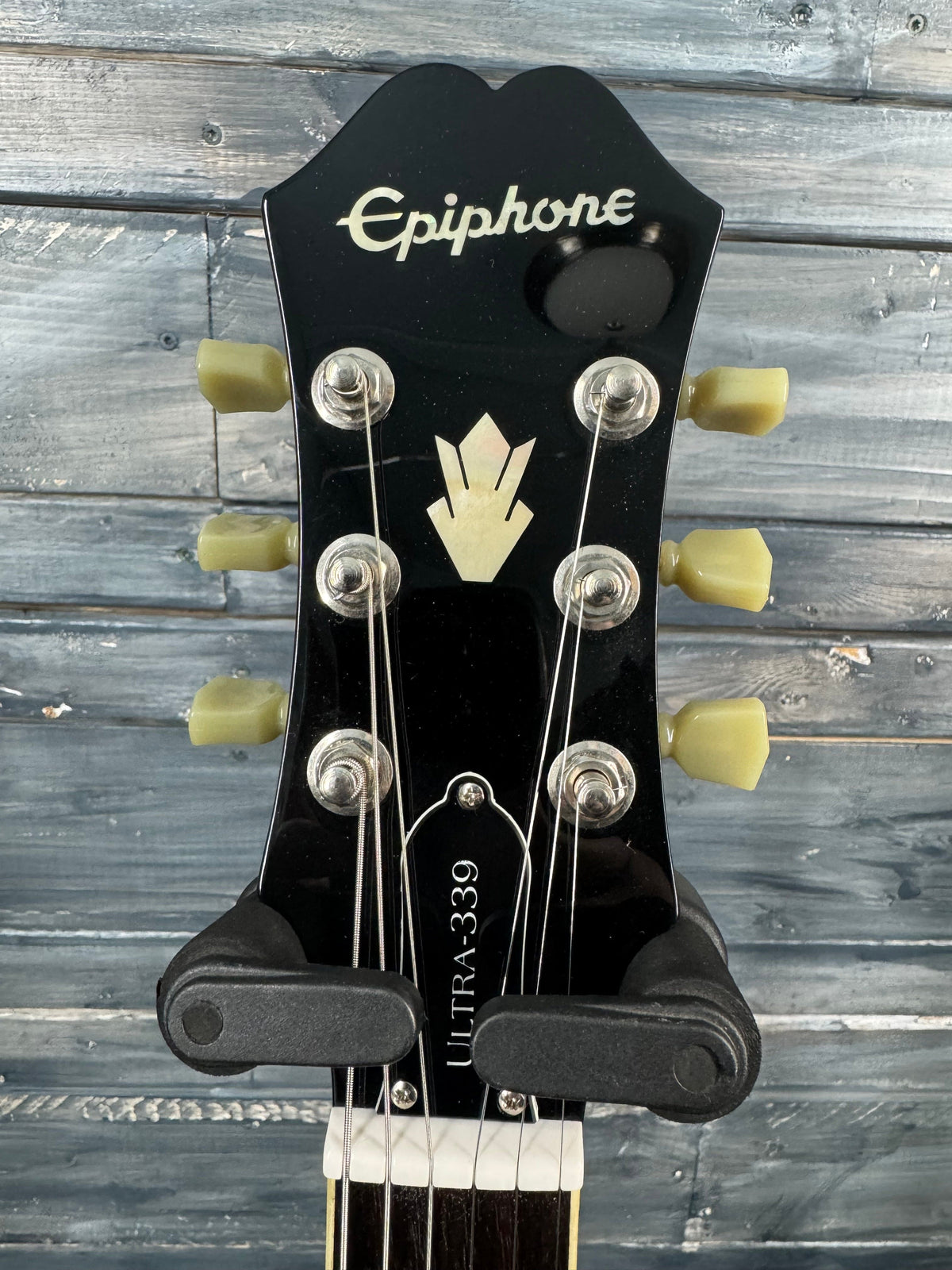 Epiphone guitar headstock with brand name against a wooden background
