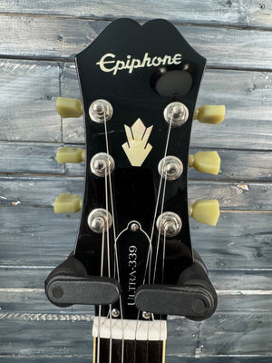 Epiphone guitar headstock with brand name against a wooden background