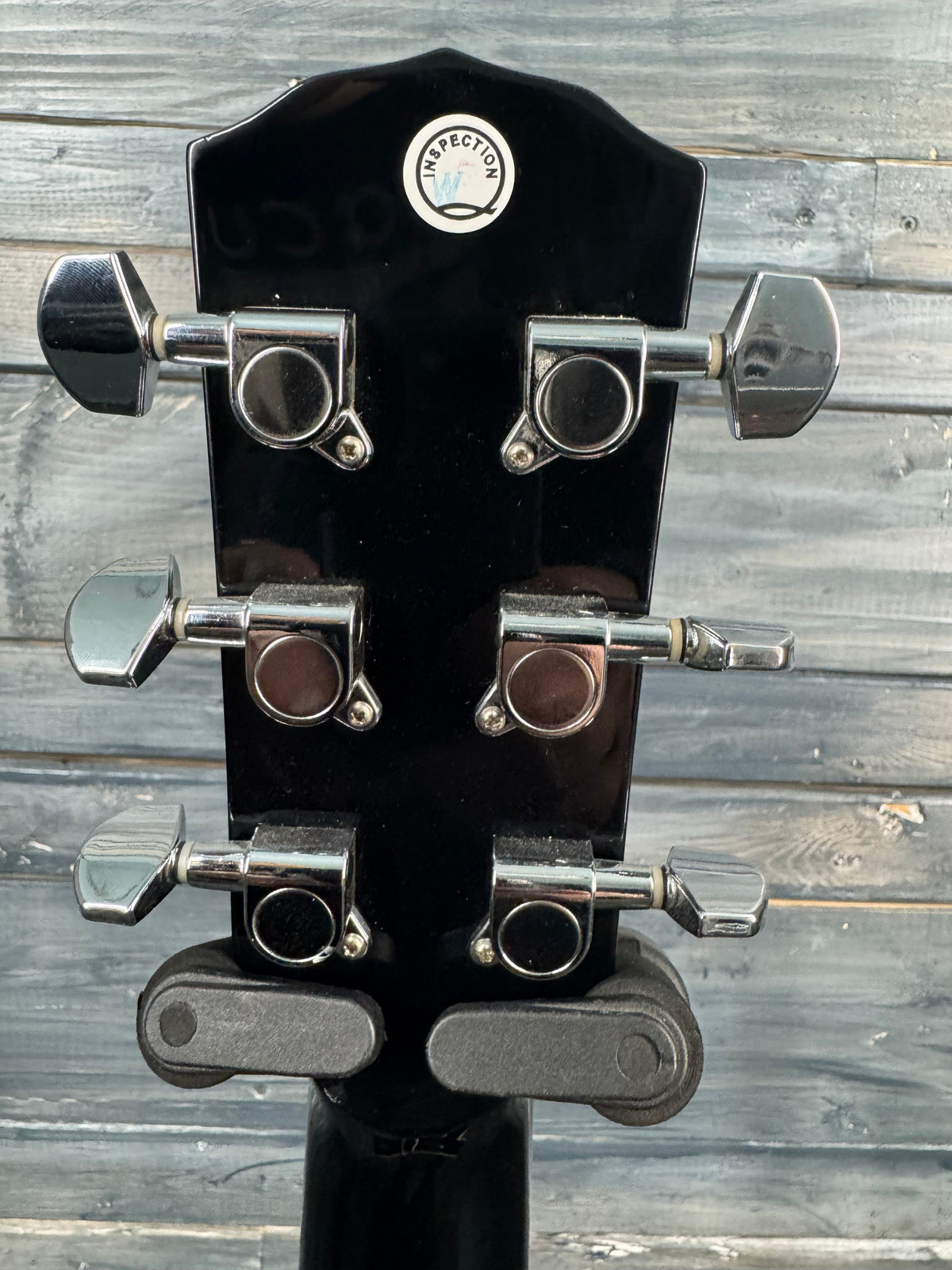 Guitar headstock with tuning pegs against a wooden background