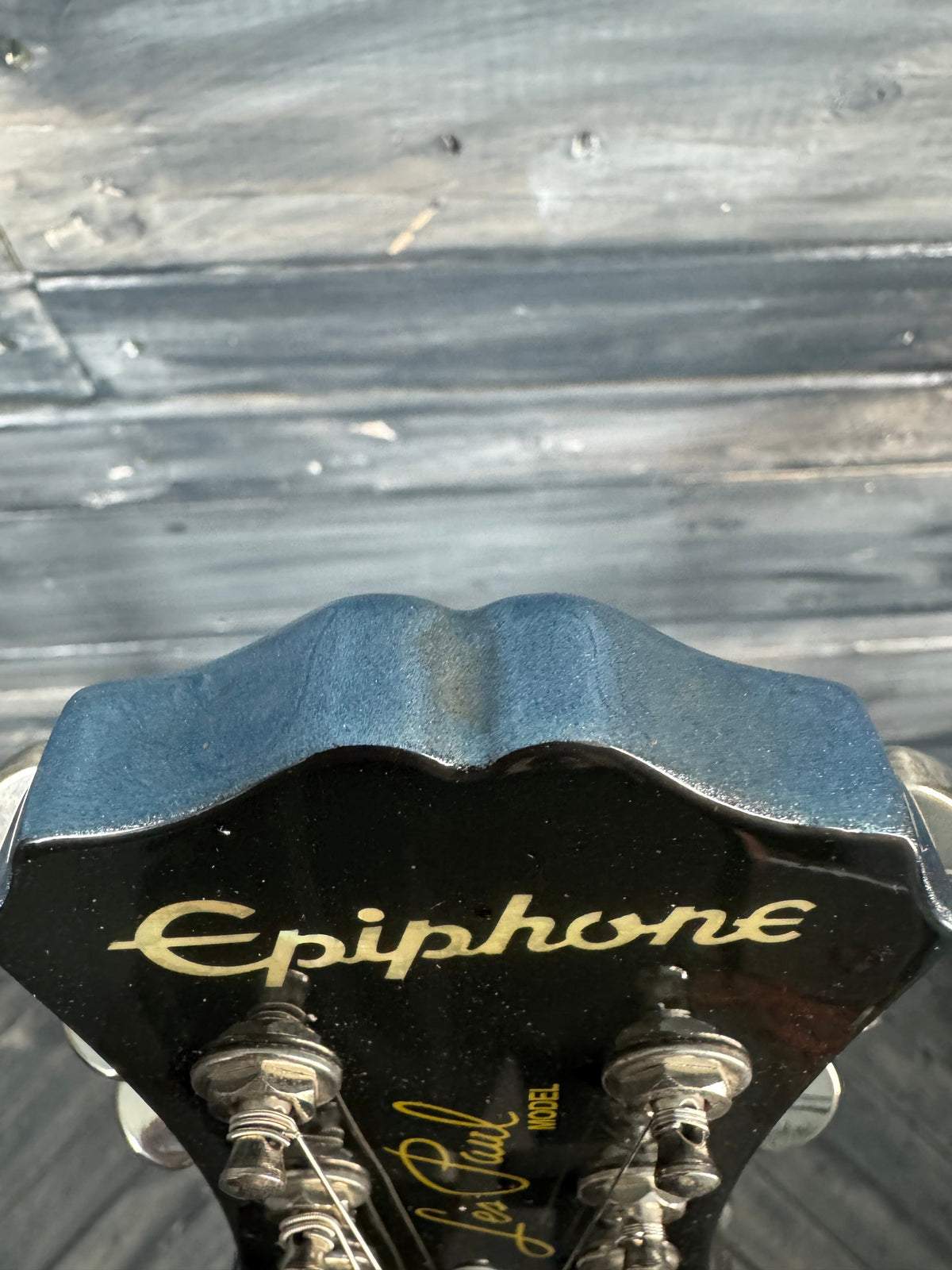 Close-up of a guitar headstock with 'Epiphone' branding against a wooden background