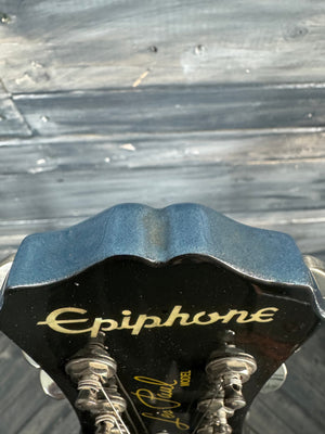 Close-up of a guitar headstock with 'Epiphone' branding against a wooden background