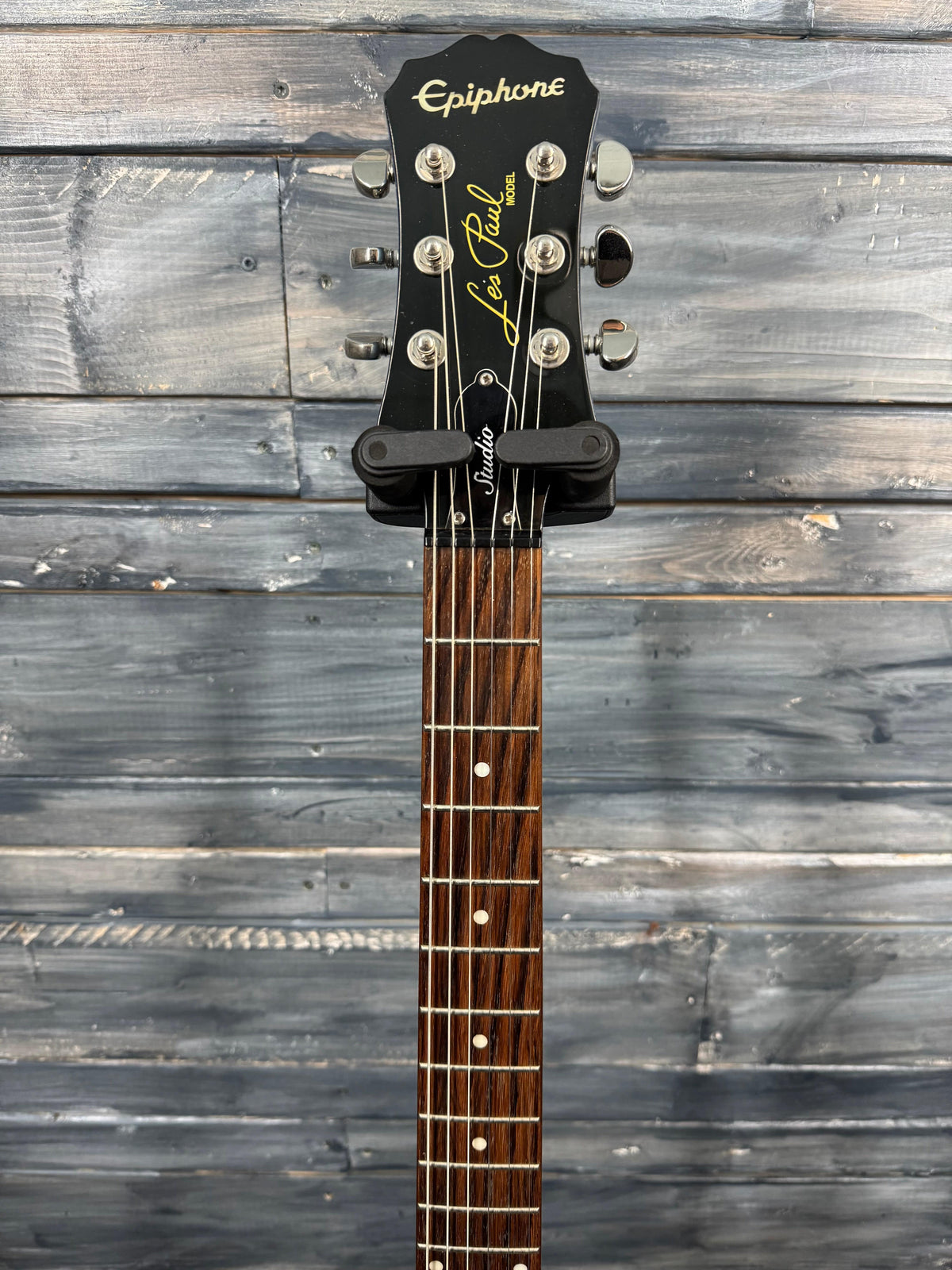 Guitar headstock with 'Epiphone' branding against a wooden background