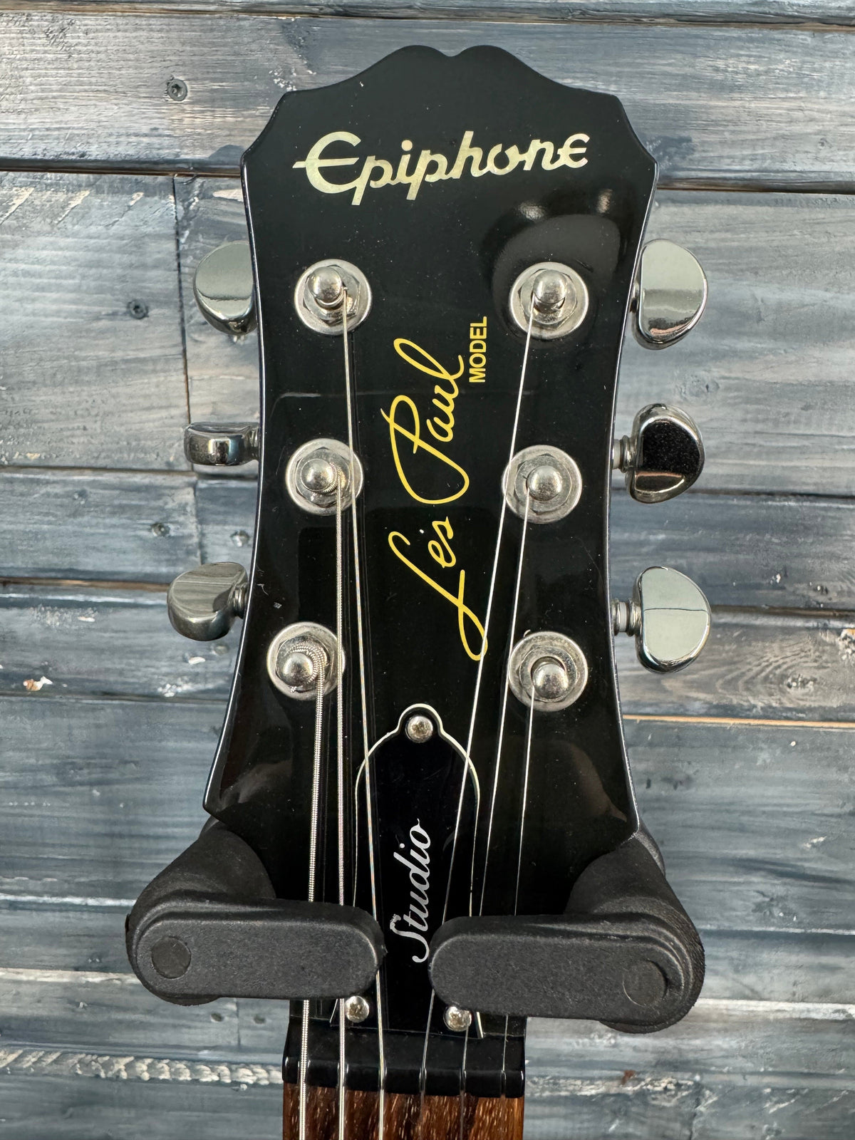 Guitar headstock with 'Epiphone' branding against a wooden background