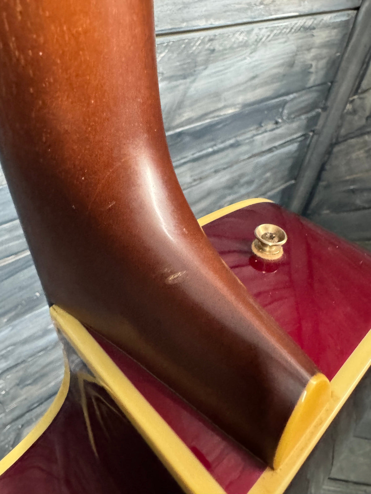 Close-up of a guitar's neck and headstock on a wooden floor.