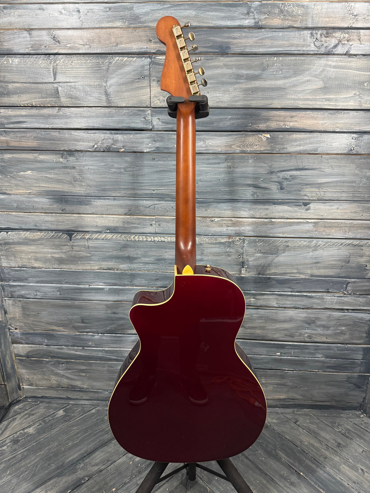 Red electric guitar against a wooden panel background