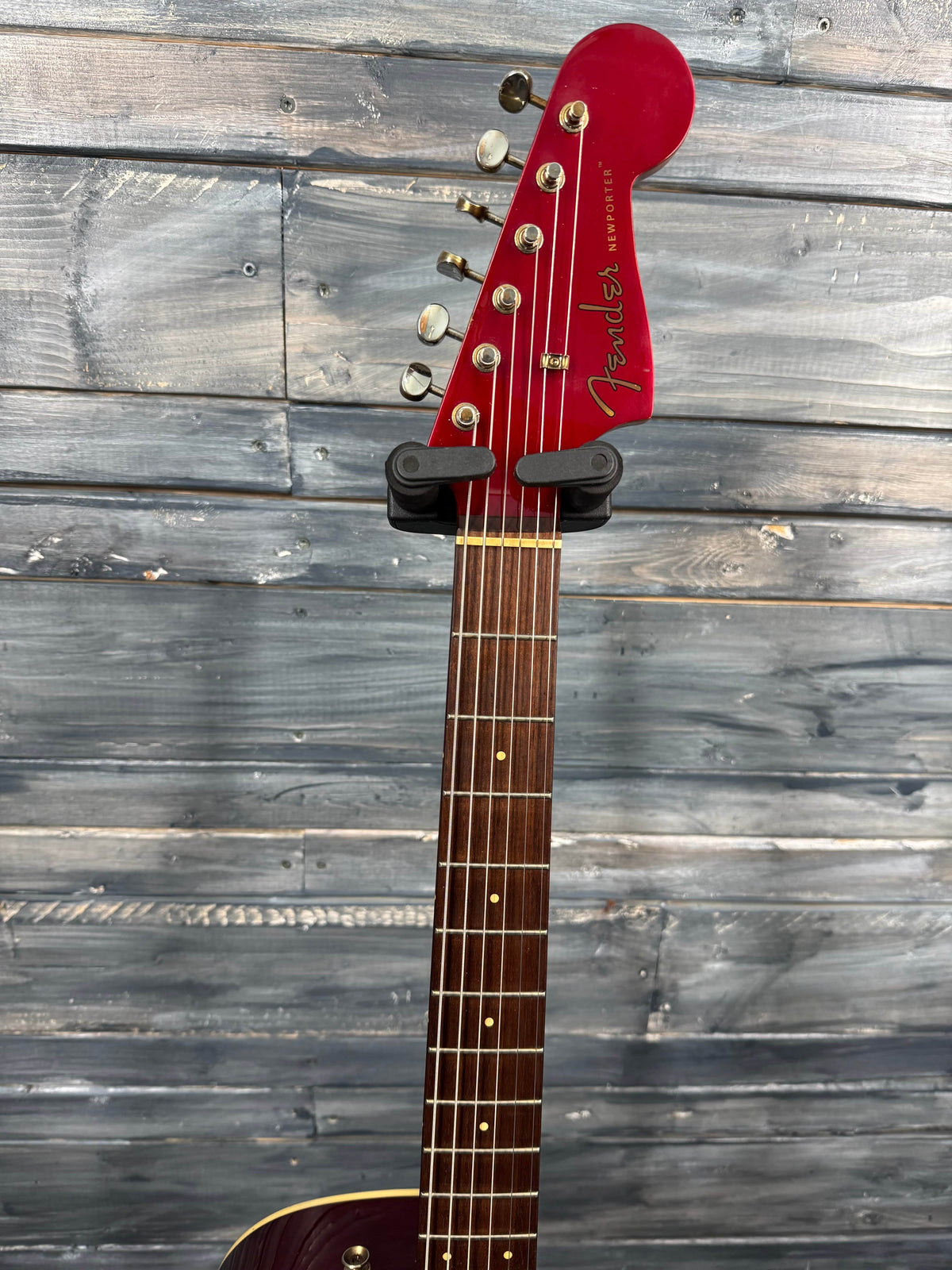 Guitar headstock with red pickguard against a wooden background