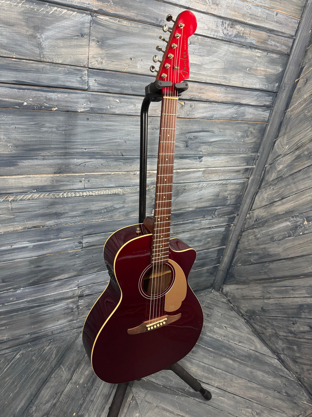 Acoustic guitar on a stand against a wooden background