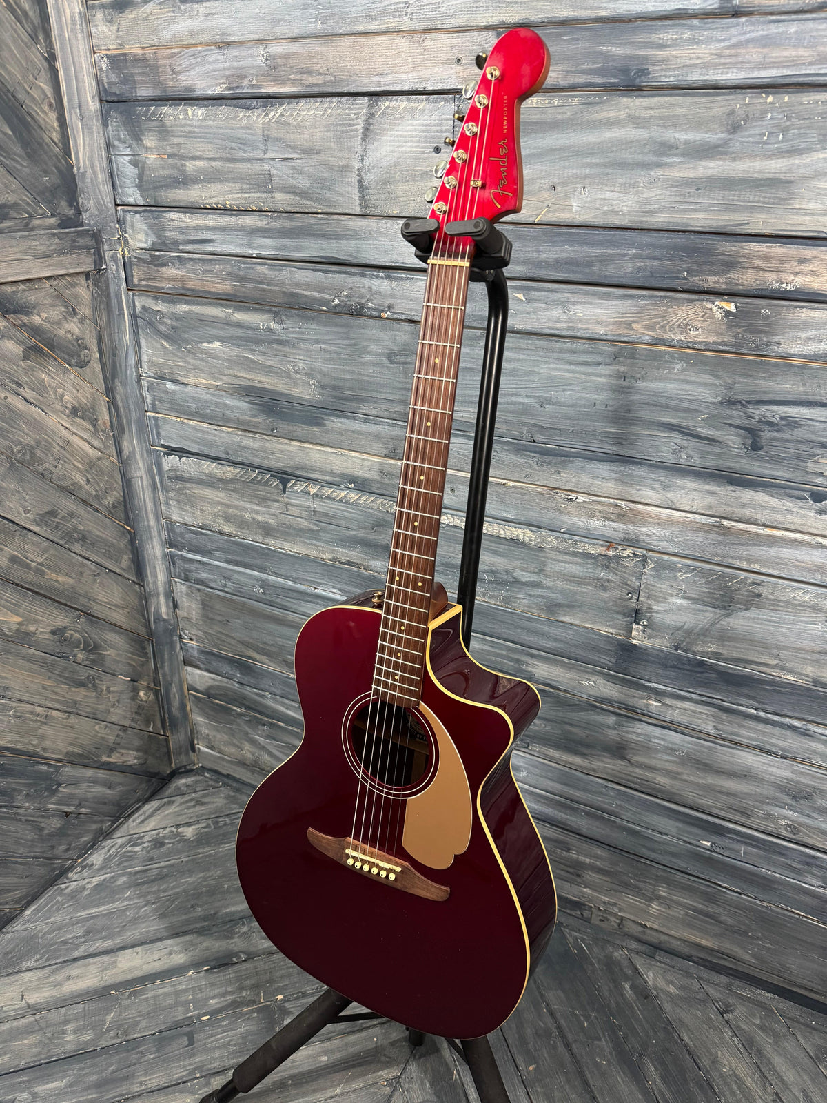 Acoustic guitar on a stand against a wooden background