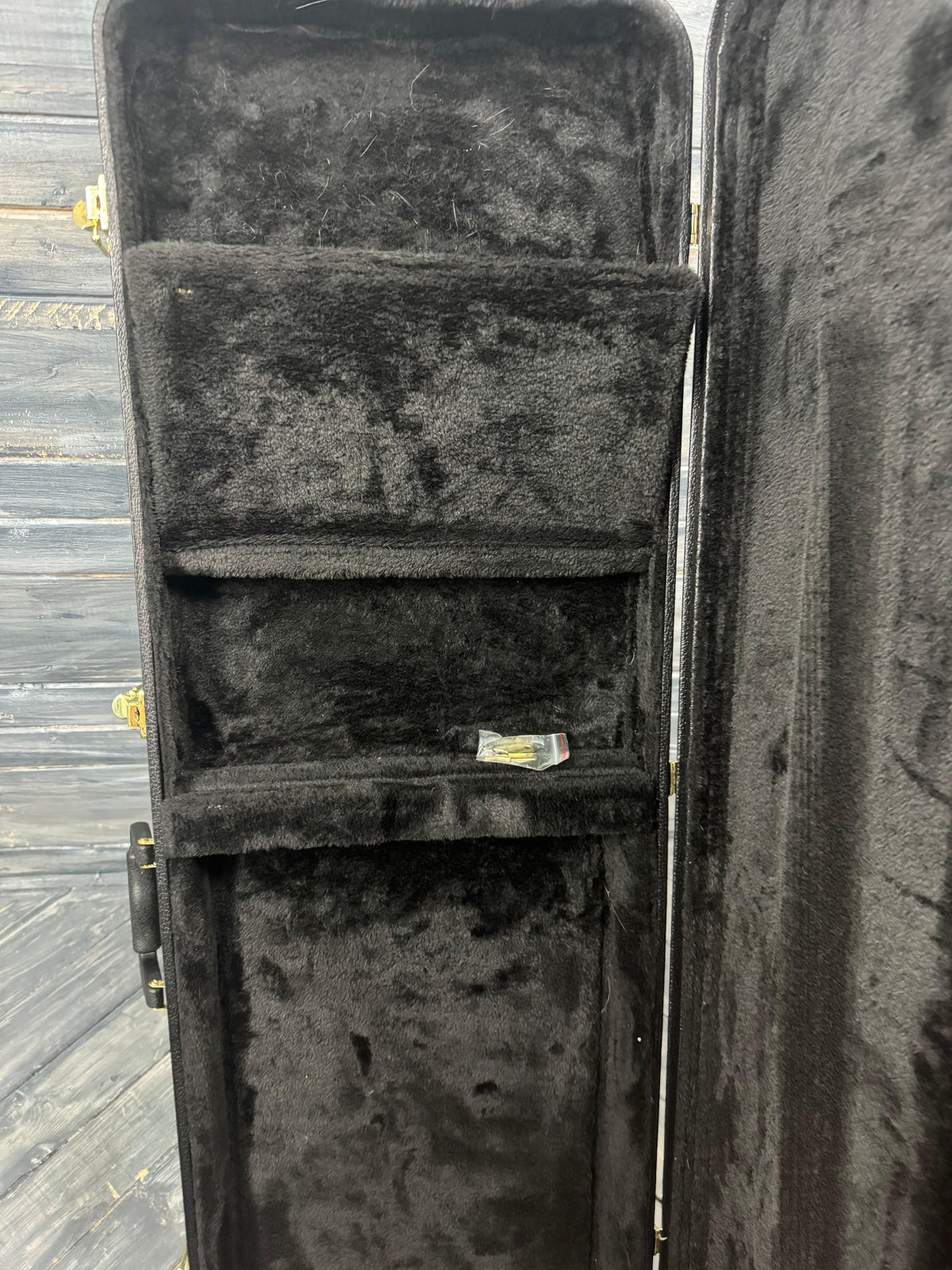 Black guitar case with interior padding on a wooden floor