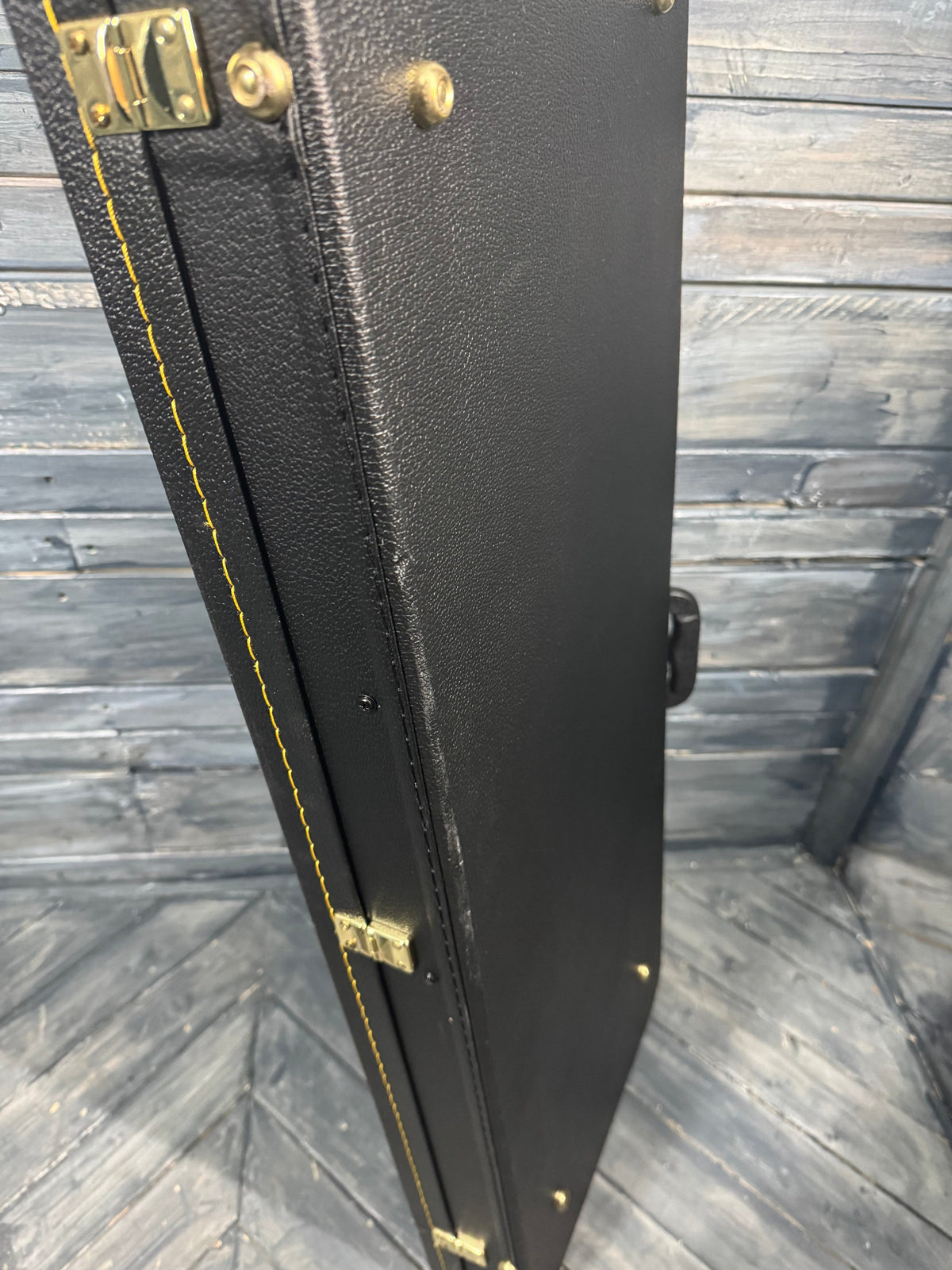 Black guitar case with gold hardware on a wooden floor