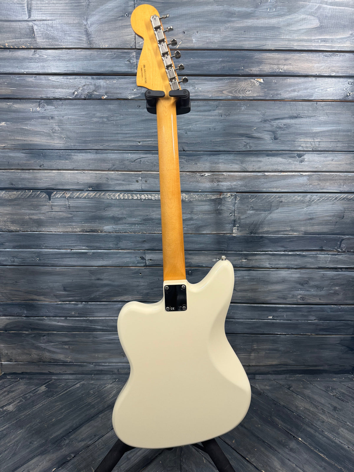 White electric guitar with a blonde neck against a wooden background
