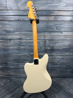 White electric guitar with a blonde neck against a wooden background