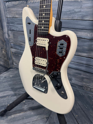 White electric guitar with a dark fretboard on a wooden background