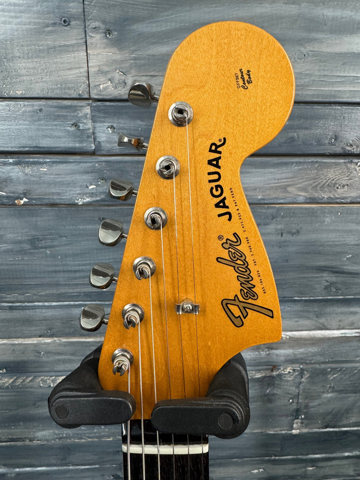 Fender Jaguar guitar headstock against a wooden background