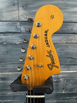 Fender Jaguar guitar headstock against a wooden background