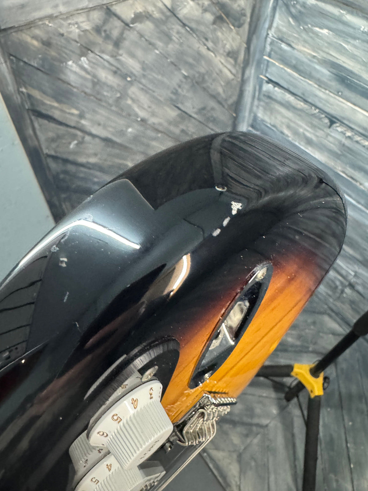 Close-up of a guitar with a worn neck on a wooden surface