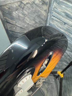 Close-up of a guitar with a worn neck on a wooden surface
