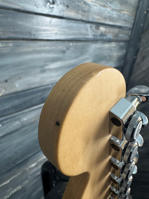 Close-up of a guitar's headstock with tuning pegs on a wooden surface