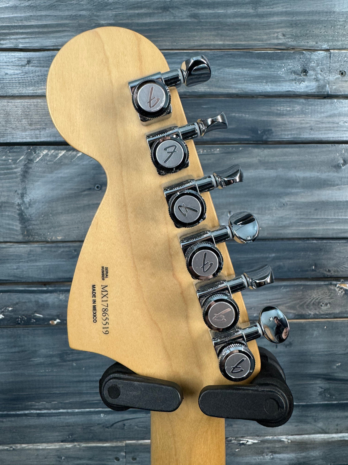Guitar headstock with tuning pegs against a wooden background
