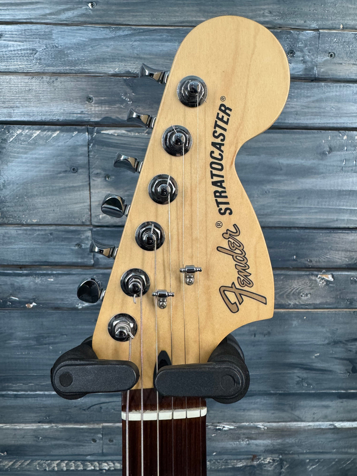 Fender Stratocaster guitar headstock against a wooden background