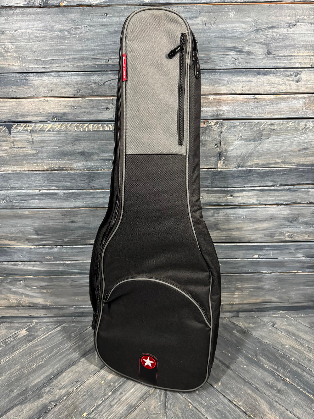 Guitar case on a wooden floor with a brand logo.