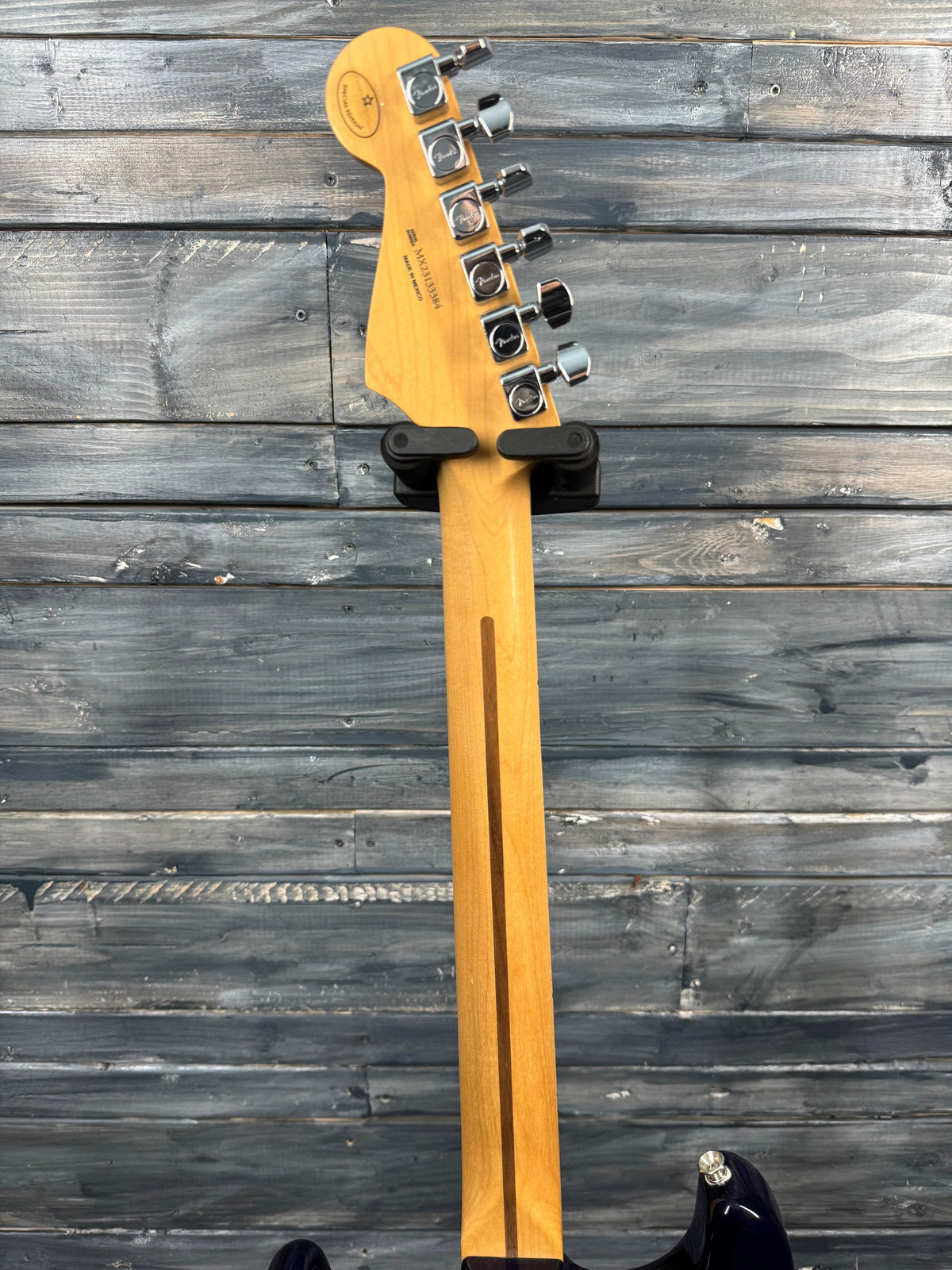 Guitar headstock with tuning pegs against a wooden background