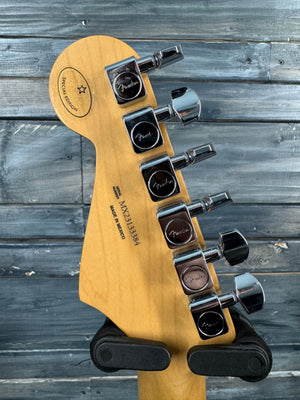 Guitar headstock with tuning pegs against a wooden background