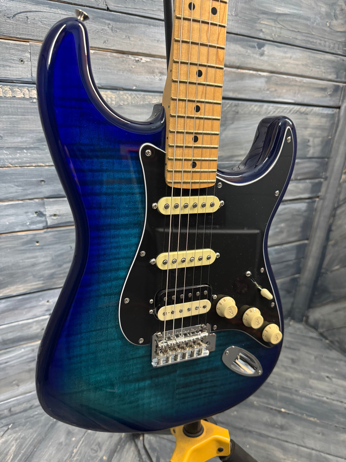 Blue electric guitar with a wooden fretboard on a wooden surface