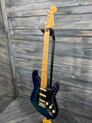 Blue electric guitar leaning against a wooden wall.