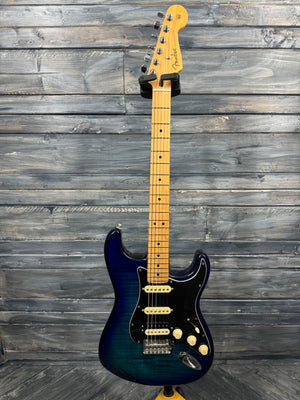 Electric guitar with a blue and black finish against a wooden background