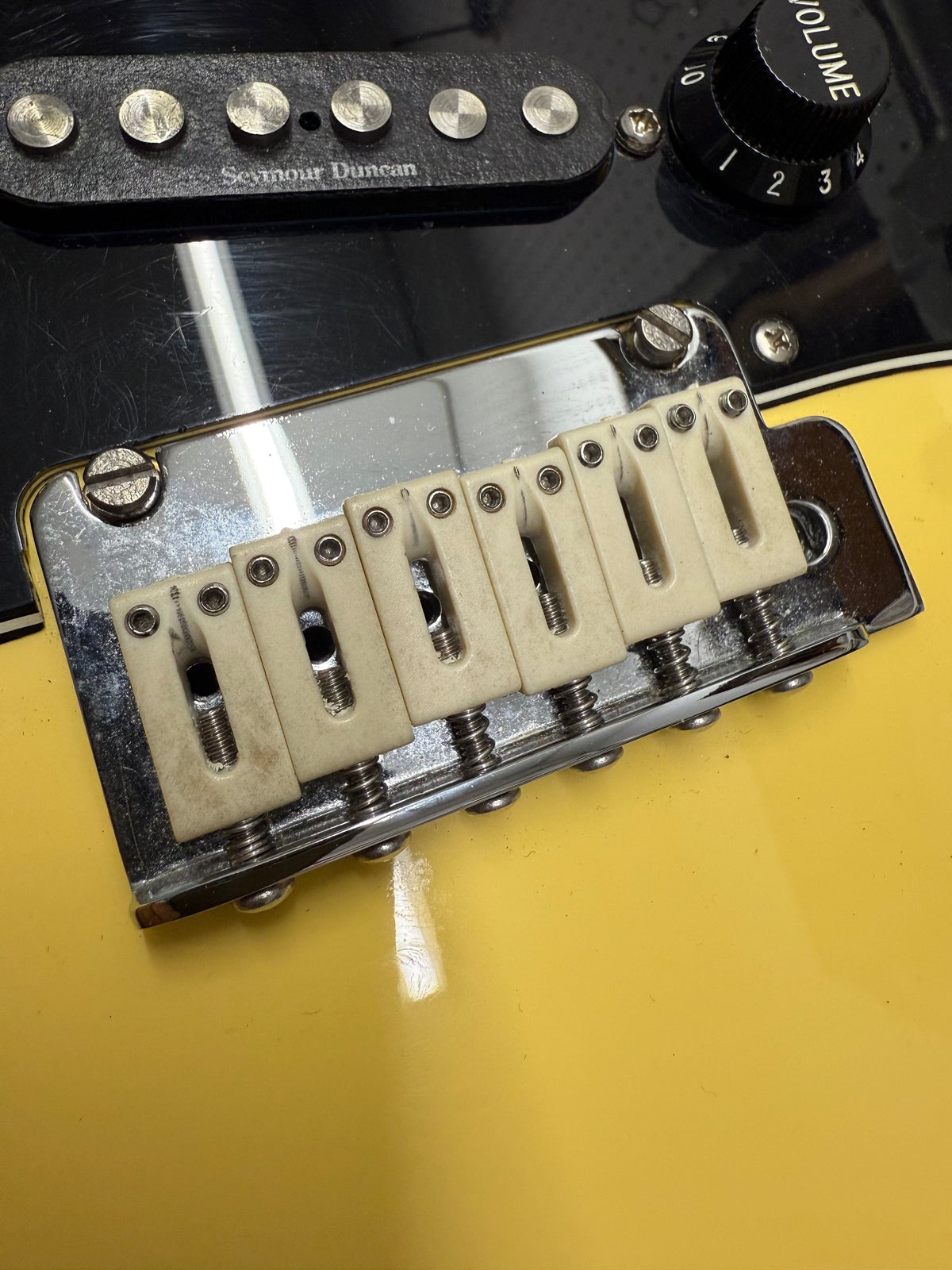 Guitar bridge with tremolo system on a yellow guitar body