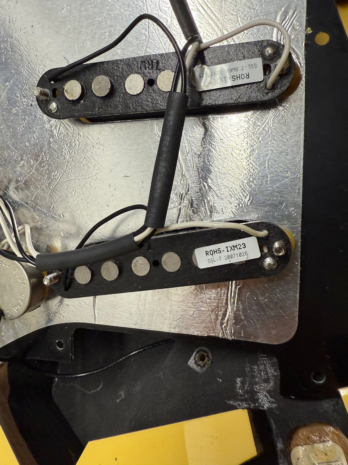 Close-up of a guitar pickup and wiring on a metallic surface