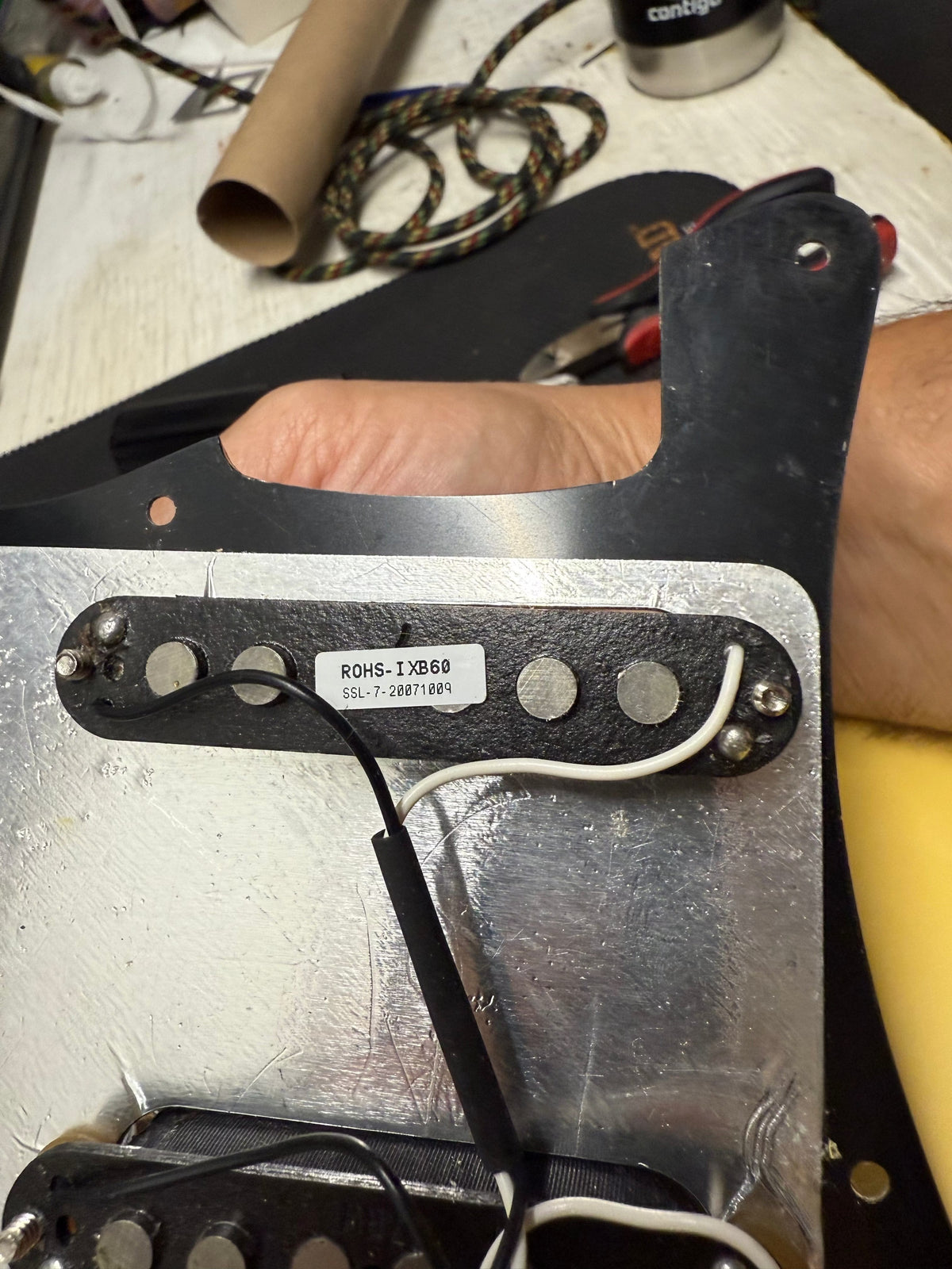 Guitar pickup with visible branding and model number on a workbench.