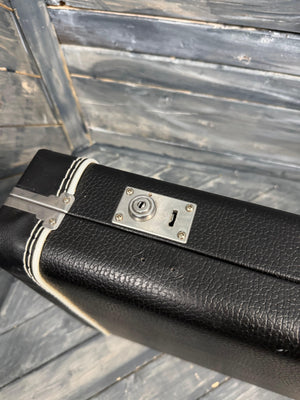 Black leather suitcase with a silver lock on a wooden surface