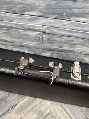 Black guitar case with silver latches on a wooden surface