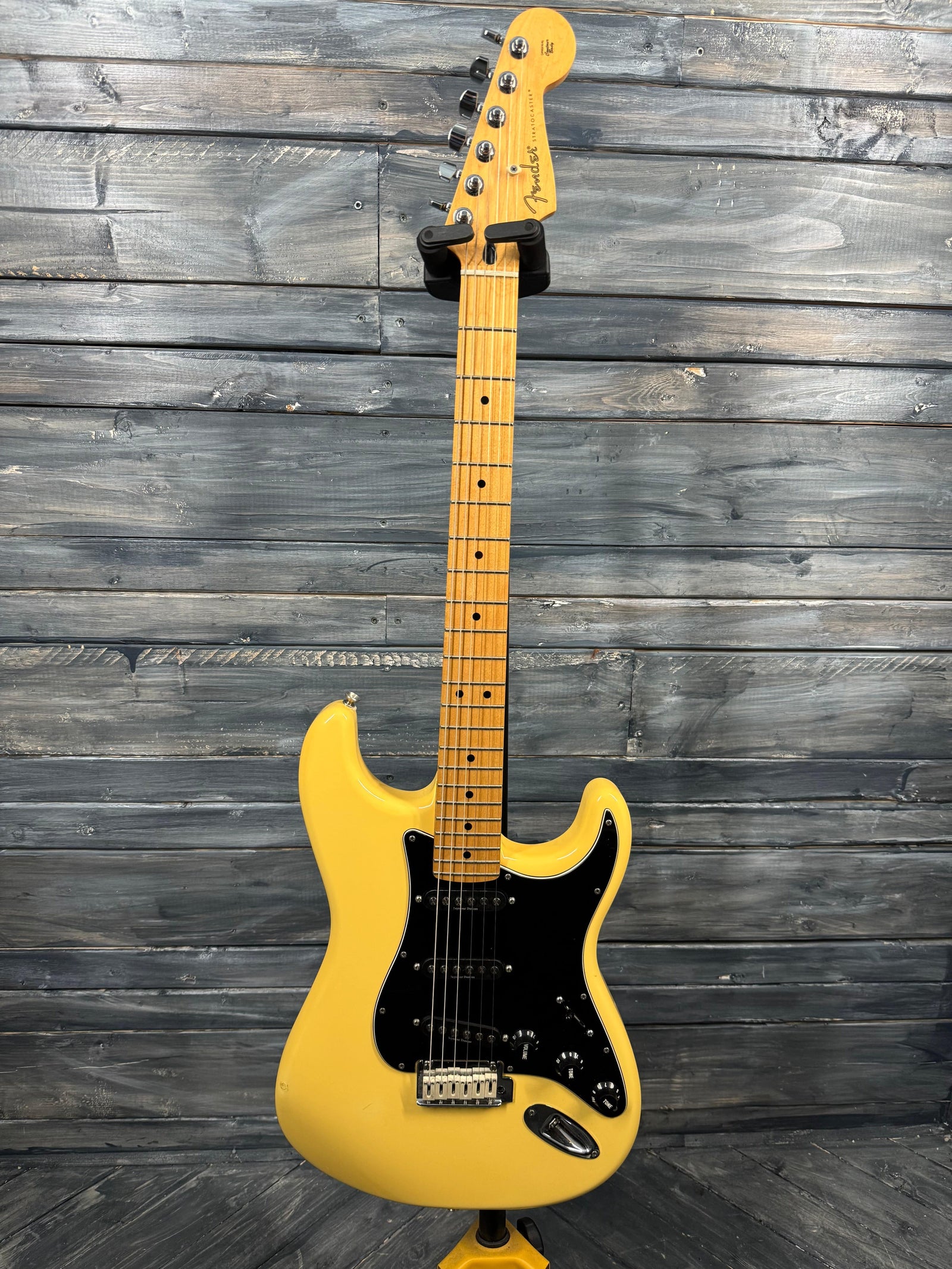 Yellow electric guitar against a wooden background