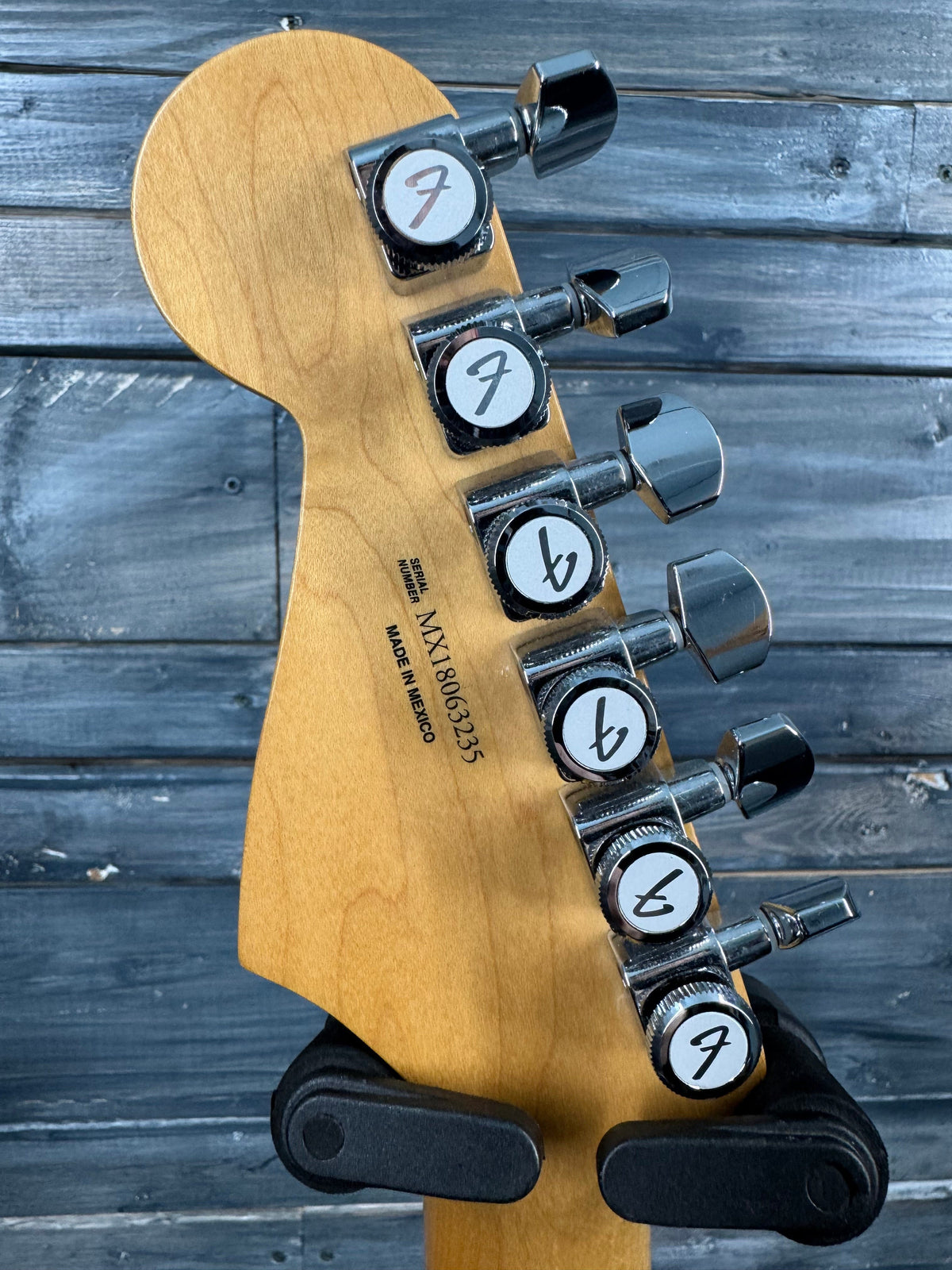 Guitar headstock with tuning pegs on a wooden surface