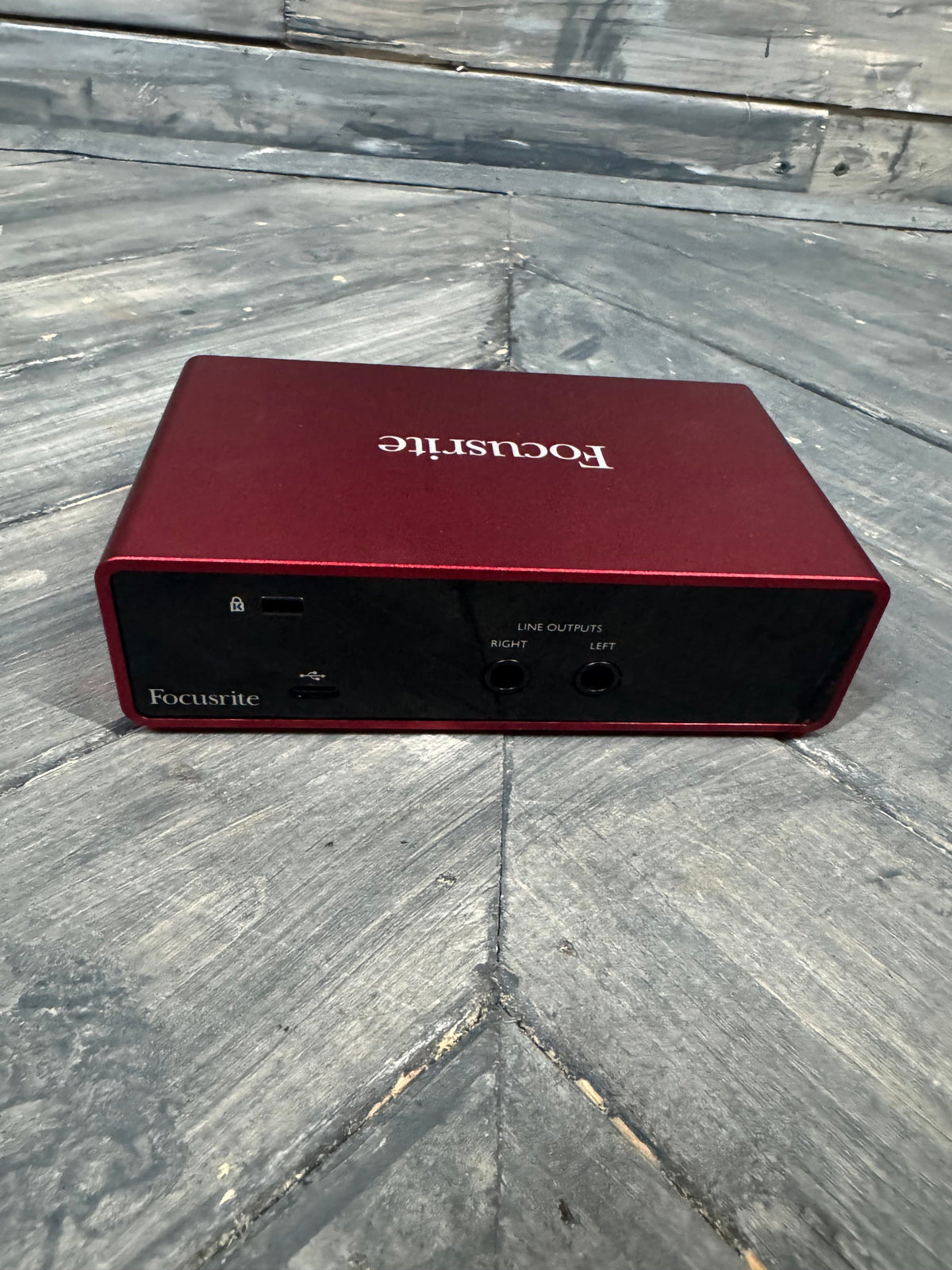 Red audio interface with 'Focusrite' branding on a gray wooden surface