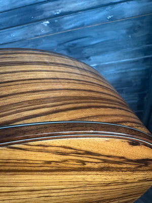 Close-up of a wooden guitar neck with a zebrawood pattern.